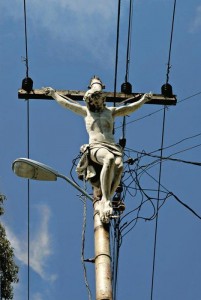 A statue of jesus crucified, mounted on a telephone pole.