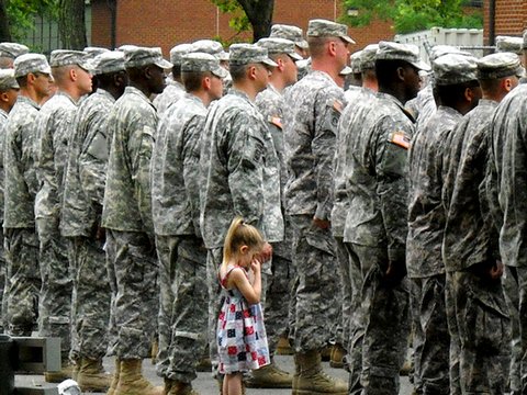 Paige Bennethum holding the hand of her father during muster. Staff Sgt. Bennethum was being deployed to Iraq.